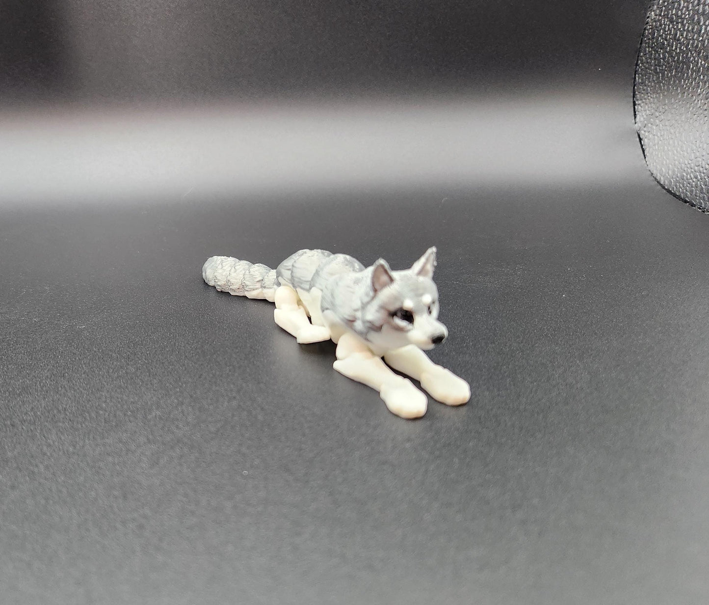 3D printed realistic wolf figurine lying down with detailed fur texture on black background