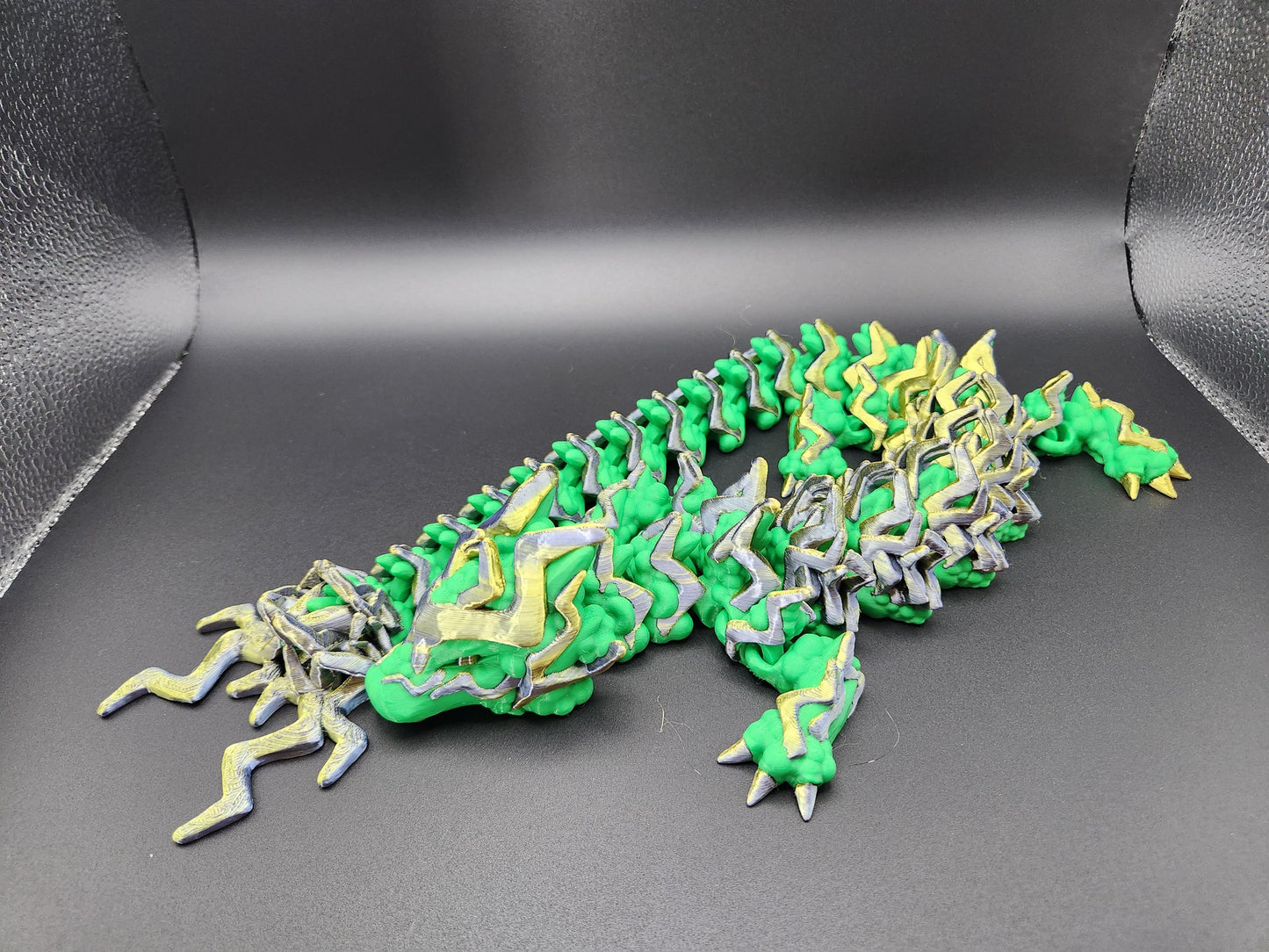 Green and yellow articulated storm dragon figurine with detailed scales and segmented body on black background