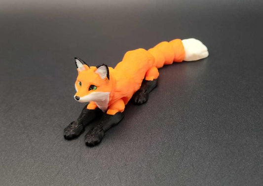 Realistic 3D printed Articulated fox figurine in orange black and white posed on a black surface