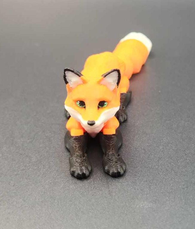 Realistic 3D printed Articulated fox figurine in orange with black legs and white tail tip on gray surface
