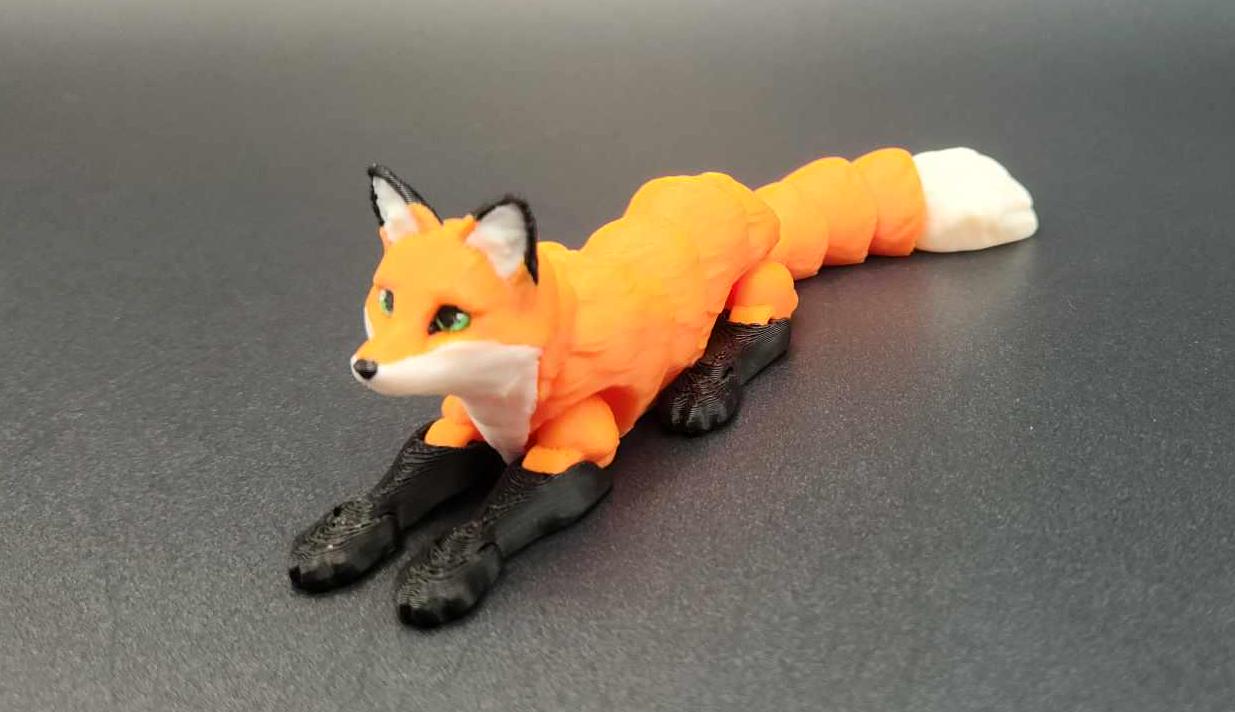 Realistic 3D printed Articulated fox figurine lying down with orange body and white tail tip