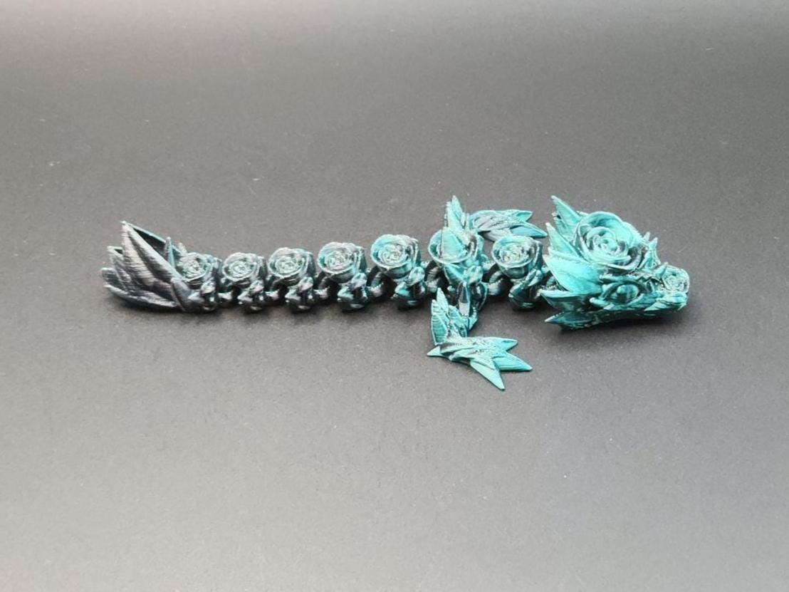 Blue 3D printed baby dragon figurine with detailed scales and wings on a dark background