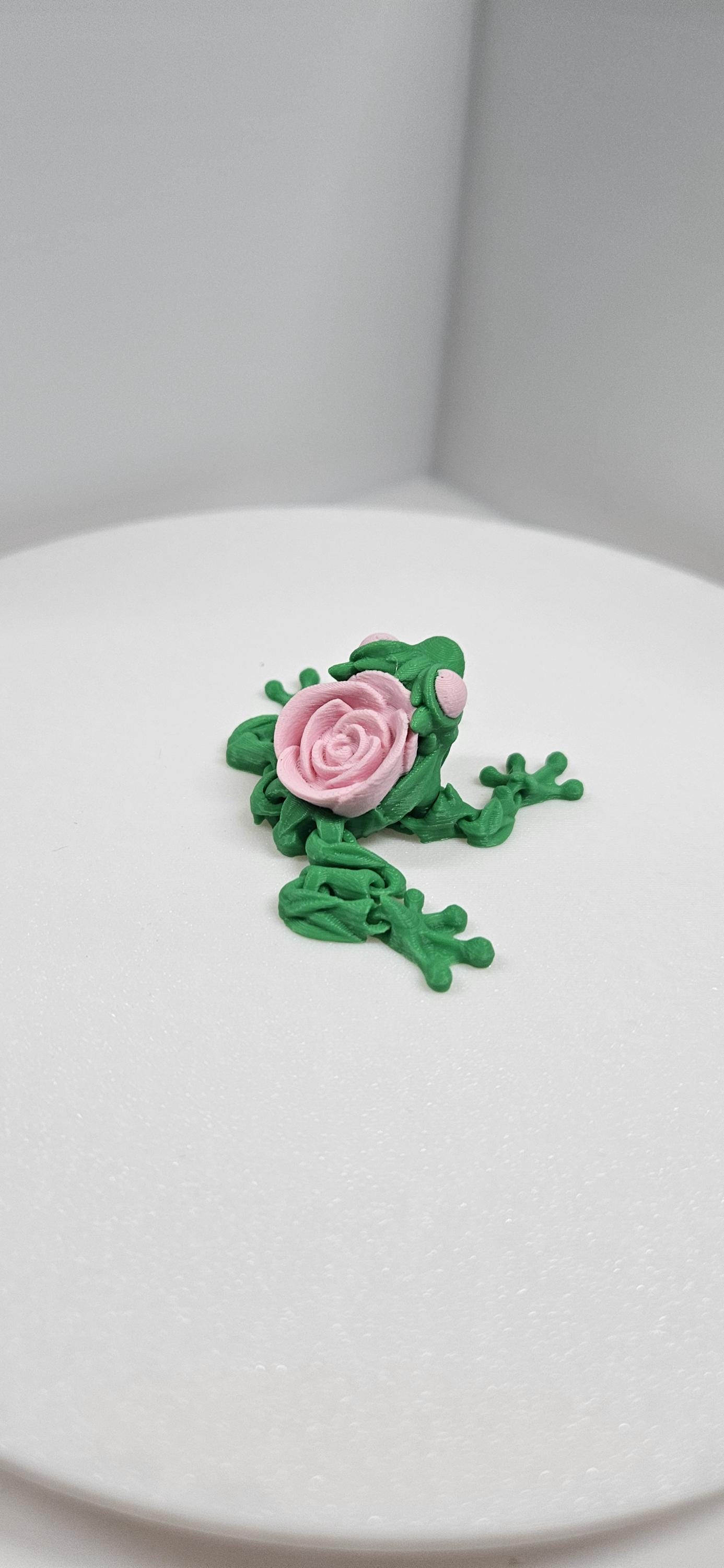 3D printed articulated rose frog figurine with green body and pink rose on back