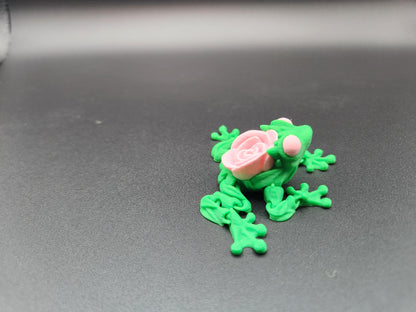 Green 3D printed articulated rose frog with pink rose detail on black background from Etsy