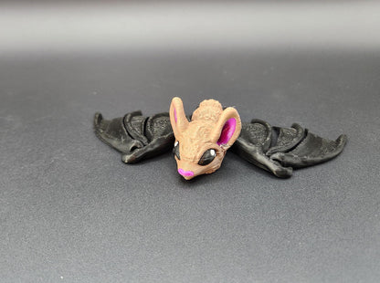 Small 3D printed bat figurine with tan face and black wings displayed on gray surface
