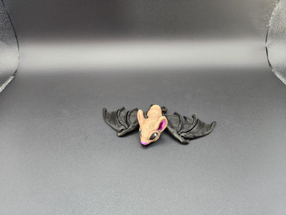 Small 3D printed bat figurine with tan head and black wings displayed on gray background
