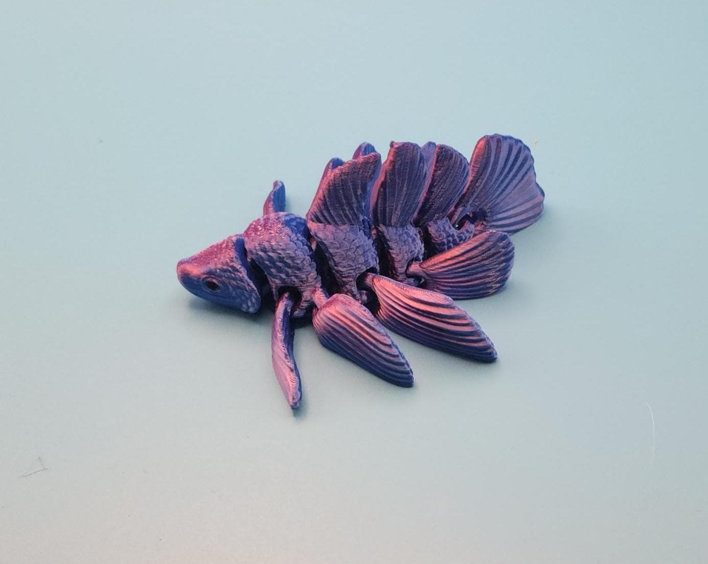 Purple and black 3D printed betta fish toy with detailed fins and textured body on a light background