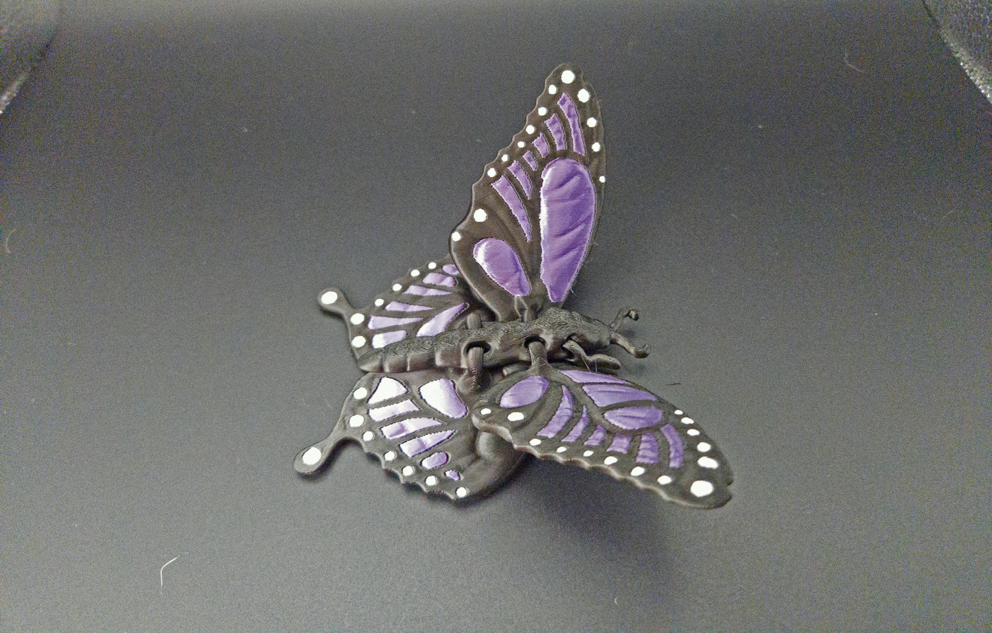 Etsy 3D printed butterfly figurine with purple and black detailed wings on a black background