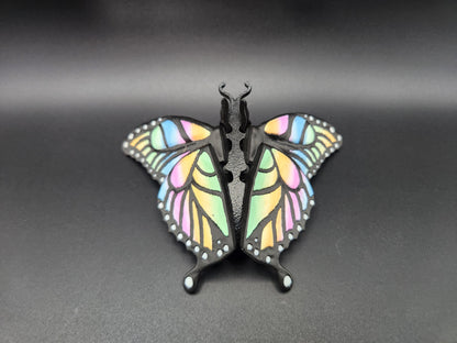 Colorful 3D printed butterfly figurine with pastel rainbow wings on a black background