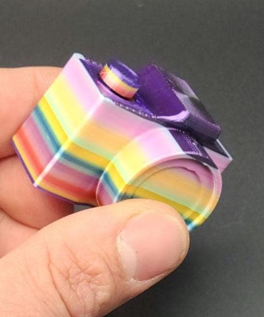 Colorful 3D printed camera fidget keychain with purple top held between fingers