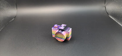 Colorful rainbow 3D printed camera fidget keychain on a dark background for stress relief