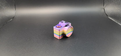 Colorful rainbow 3D printed camera fidget keychain displayed on black background