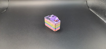 Colorful 3D printed camera fidget keychain with rainbow layers on a black background