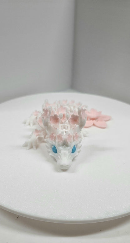 3D printed cherry blossom baby dragon figurine with white body and pink flower details on Etsy