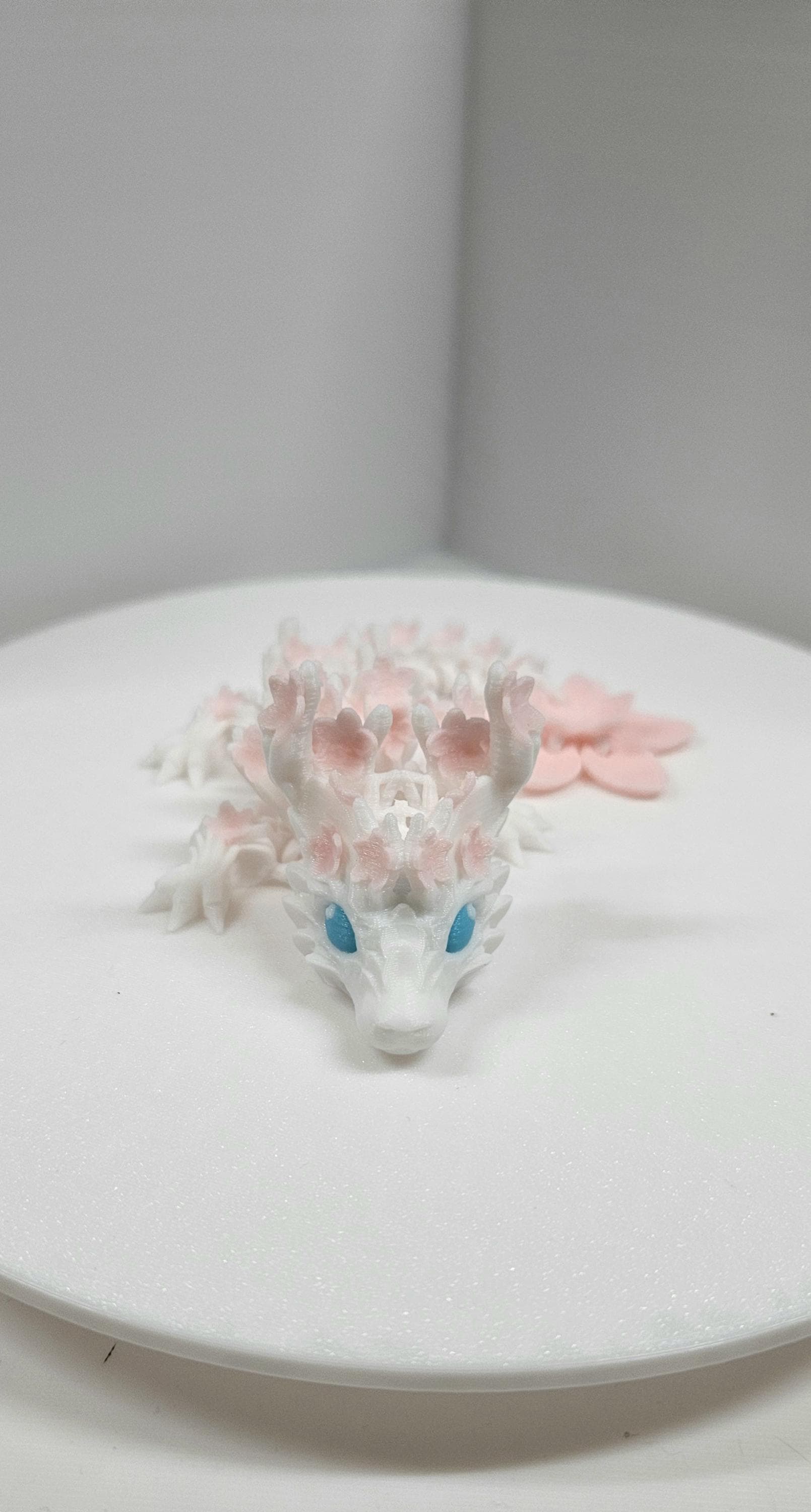 3D printed cherry blossom baby dragon figurine with blue eyes and delicate pink flower details