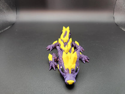 Purple and yellow 3D printed crystal dragon figurine with detailed scales and spikes on black background