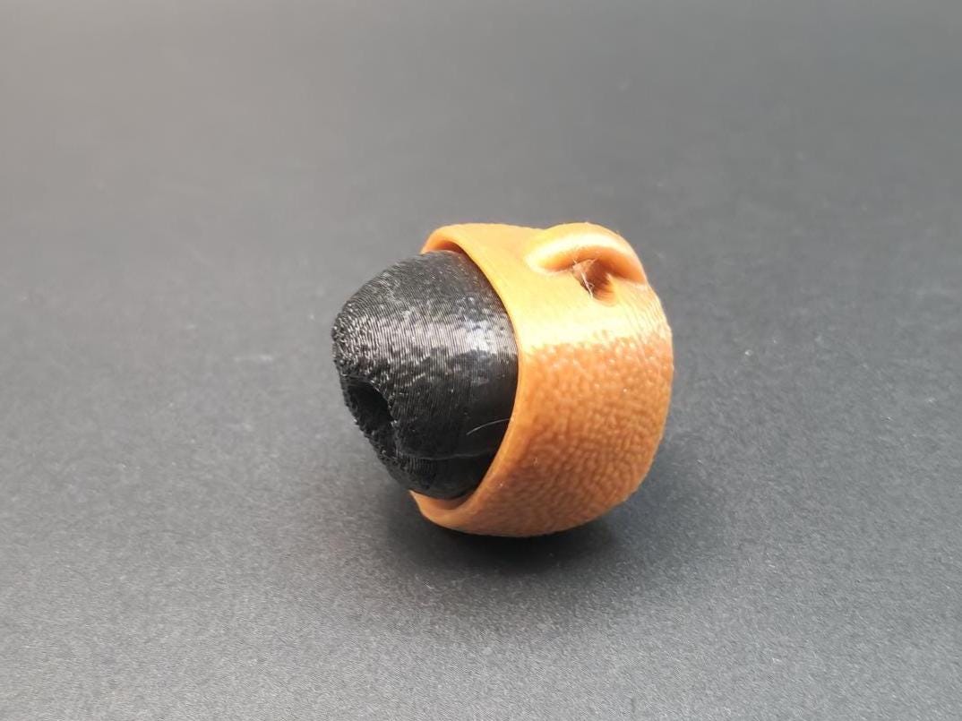 3D printed dog nose clicker keychain in black and brown with textured detail on dark background