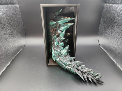 Green and black 3D printed dragon bookend with detailed scales and spikes inside a black display box