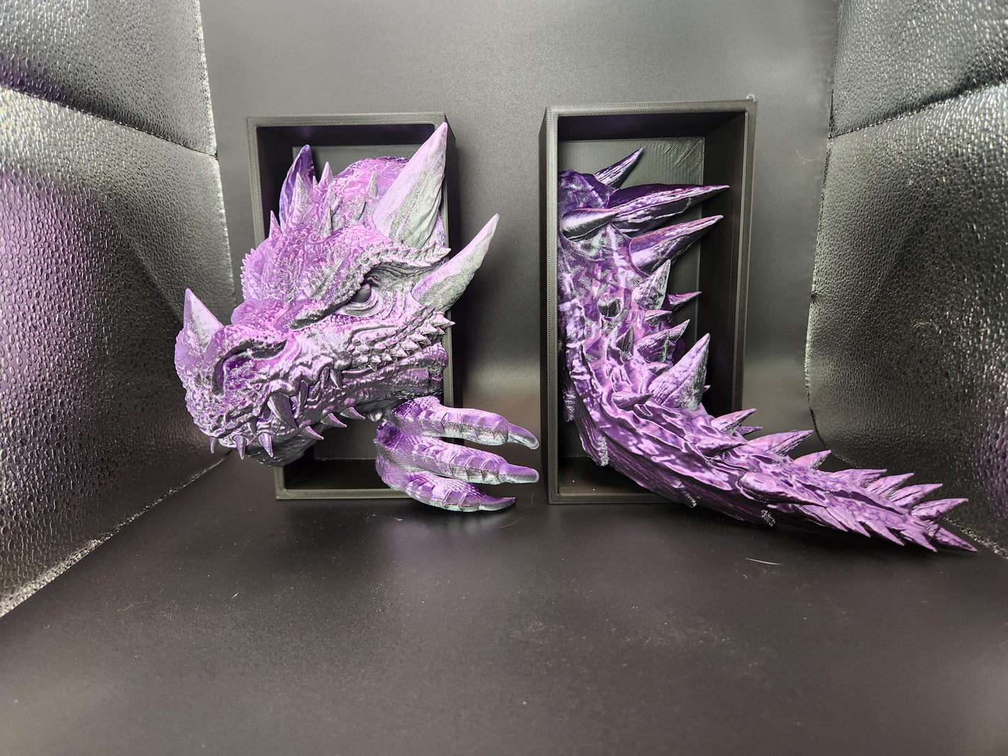 Purple 3D printed dragon bookend with detailed head and tail design on black background