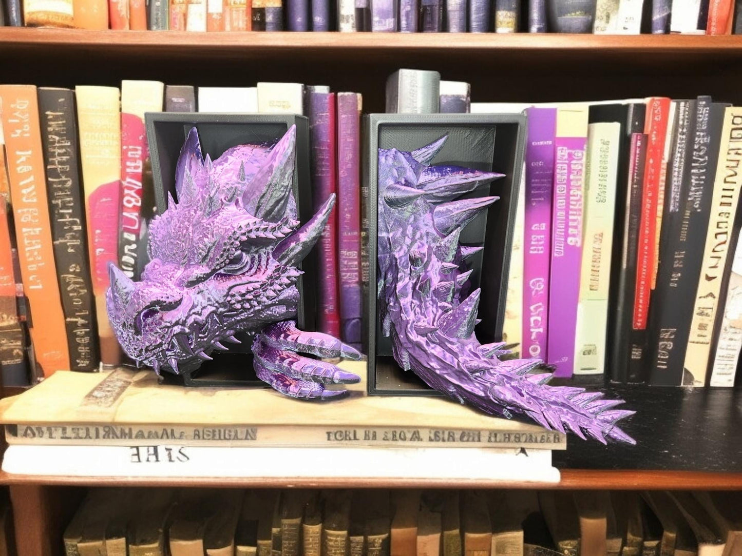 Purple 3D printed dragon bookend with detailed scales and claws holding books on a wooden shelf
