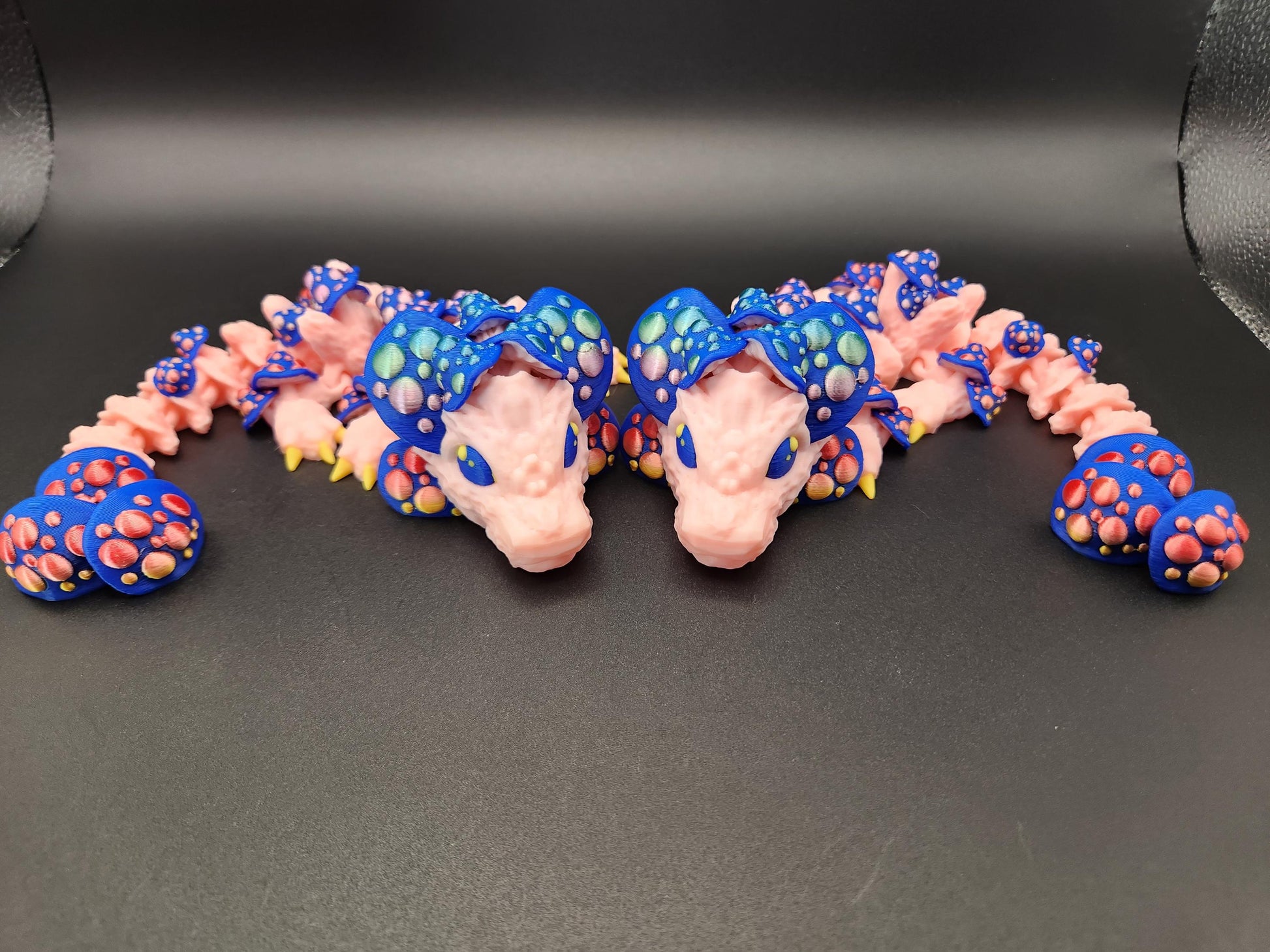 Colorful 3D printed dragon mushroom toy with blue and pink mushroom details on black background