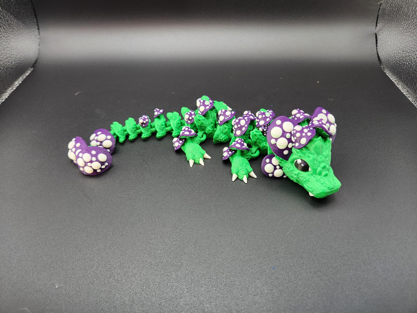 Green and purple 3D printed dragon mushroom toy with spotted mushroom details on black background