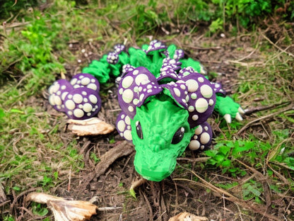 Green and purple 3D printed dragon mushroom toy with white mushroom spots on natural ground