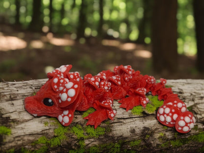 Red 3D printed dragon mushroom toy with white spots resting on a mossy tree log outdoors