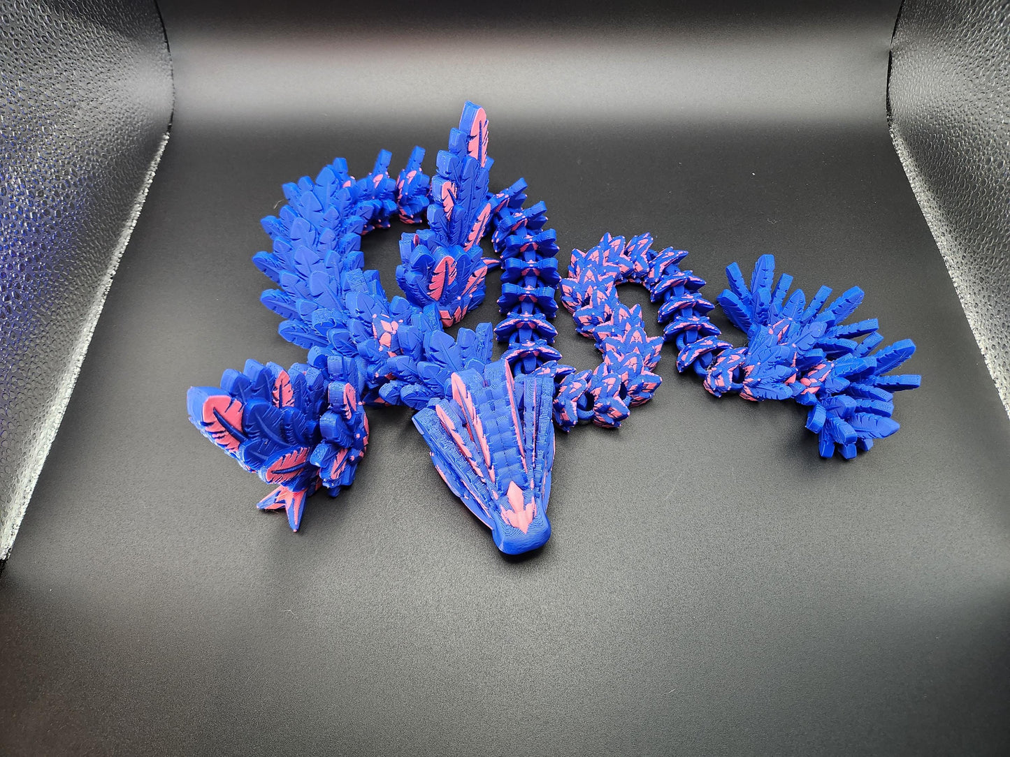 Blue and pink 3D printed feather dragon figurine with detailed scales and wings on black background