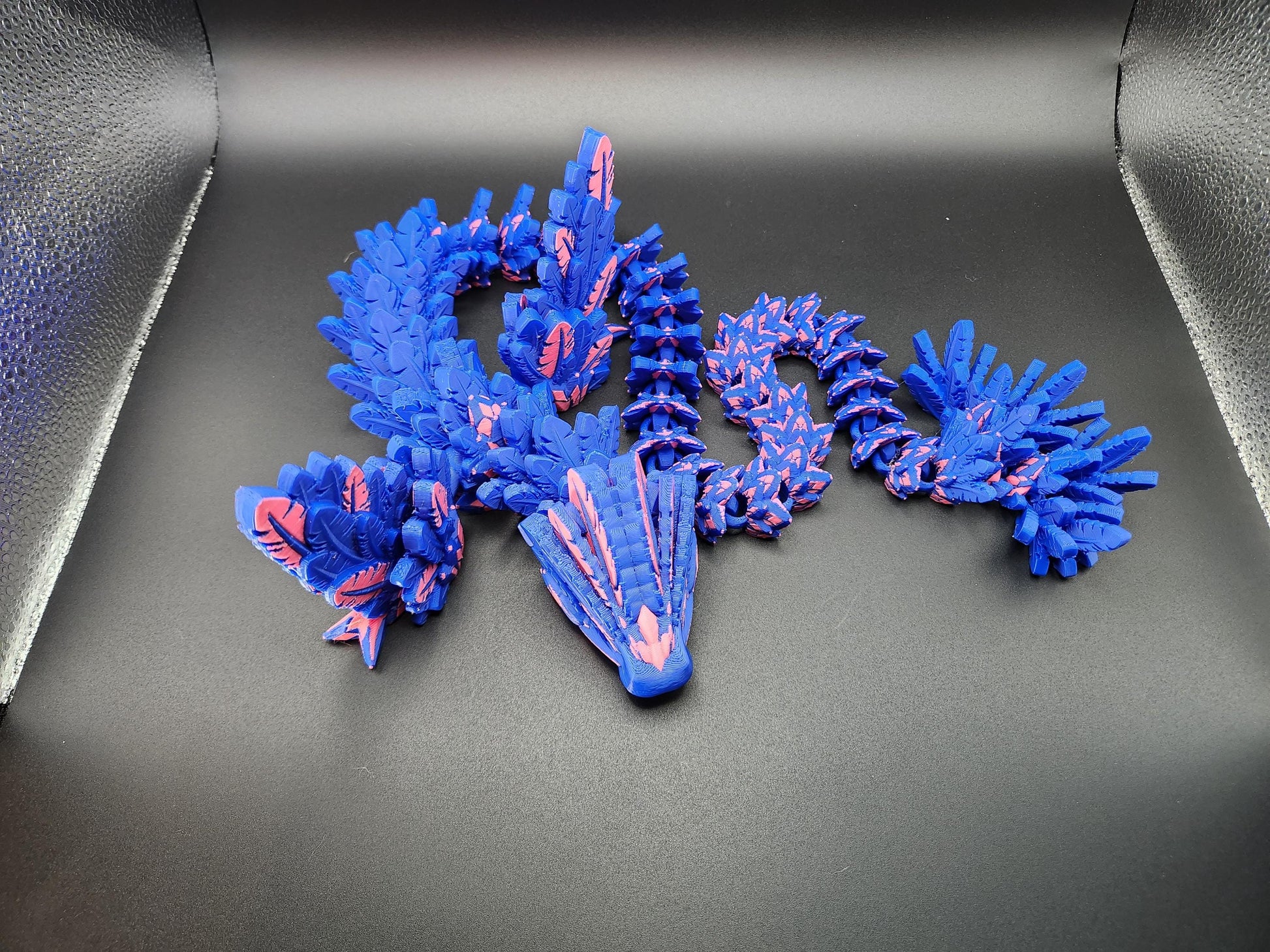 Blue and pink 3D printed feather dragon figurine with detailed scales and wings on black background