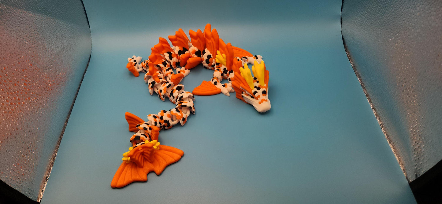 3D printed koi dragon toy with orange and white scales displayed on a blue surface