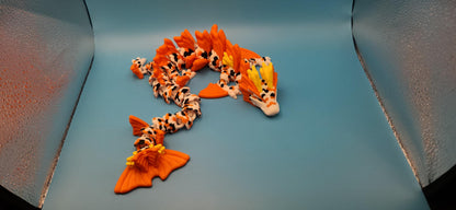3D printed koi dragon toy with orange and white scales displayed on a blue surface