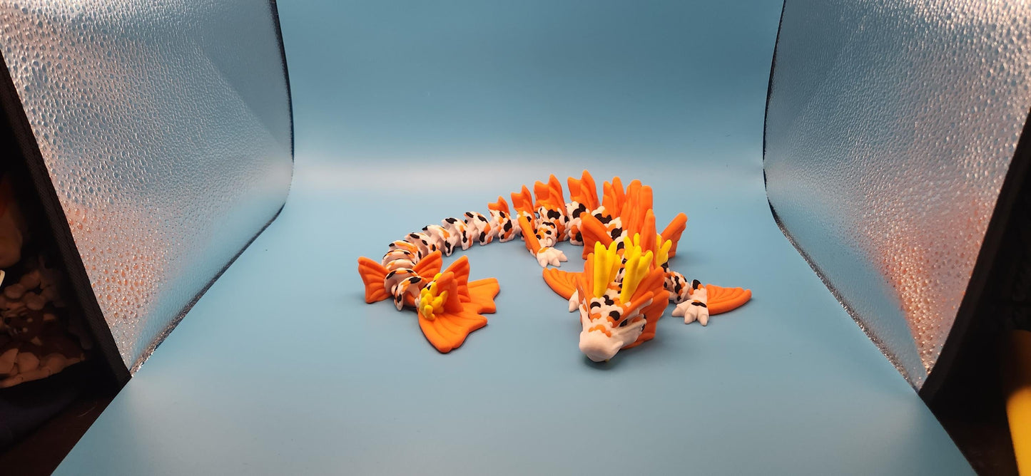 Colorful 3D printed koi dragon toy with orange and yellow details displayed on a blue surface