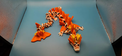 3D printed koi dragon toy in orange and white with detailed scales and fins displayed on blue background