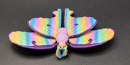 Colorful 3D printed luminous moth with rainbow stripes displayed on a dark background