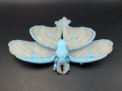 3D printed luminous moth with blue and white wings displayed on black surface