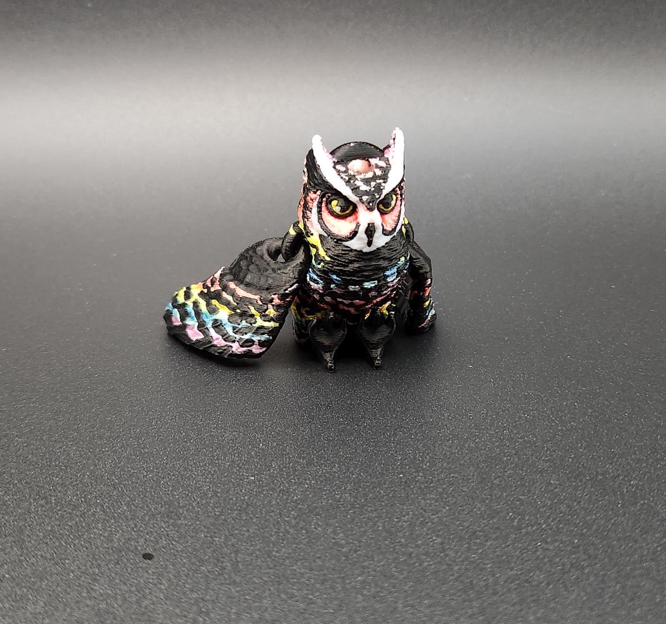Colorful 3D printed owl keychain with detailed feathers and expressive eyes on black background