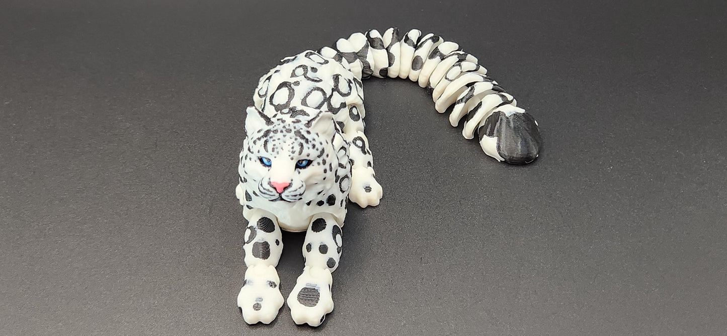3D printed snow leopard figurine in white with black spots lying on gray surface from Etsy