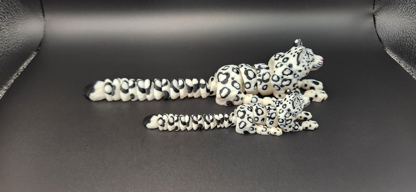 Two 3D printed snow leopard figurines in different sizes with detailed black spots on white bodies