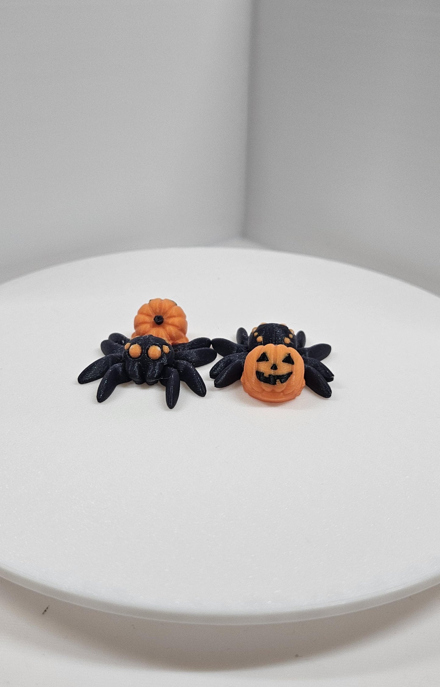 Black 3D printed spider fidget toy with pumpkin decorations for Halloween stress relief