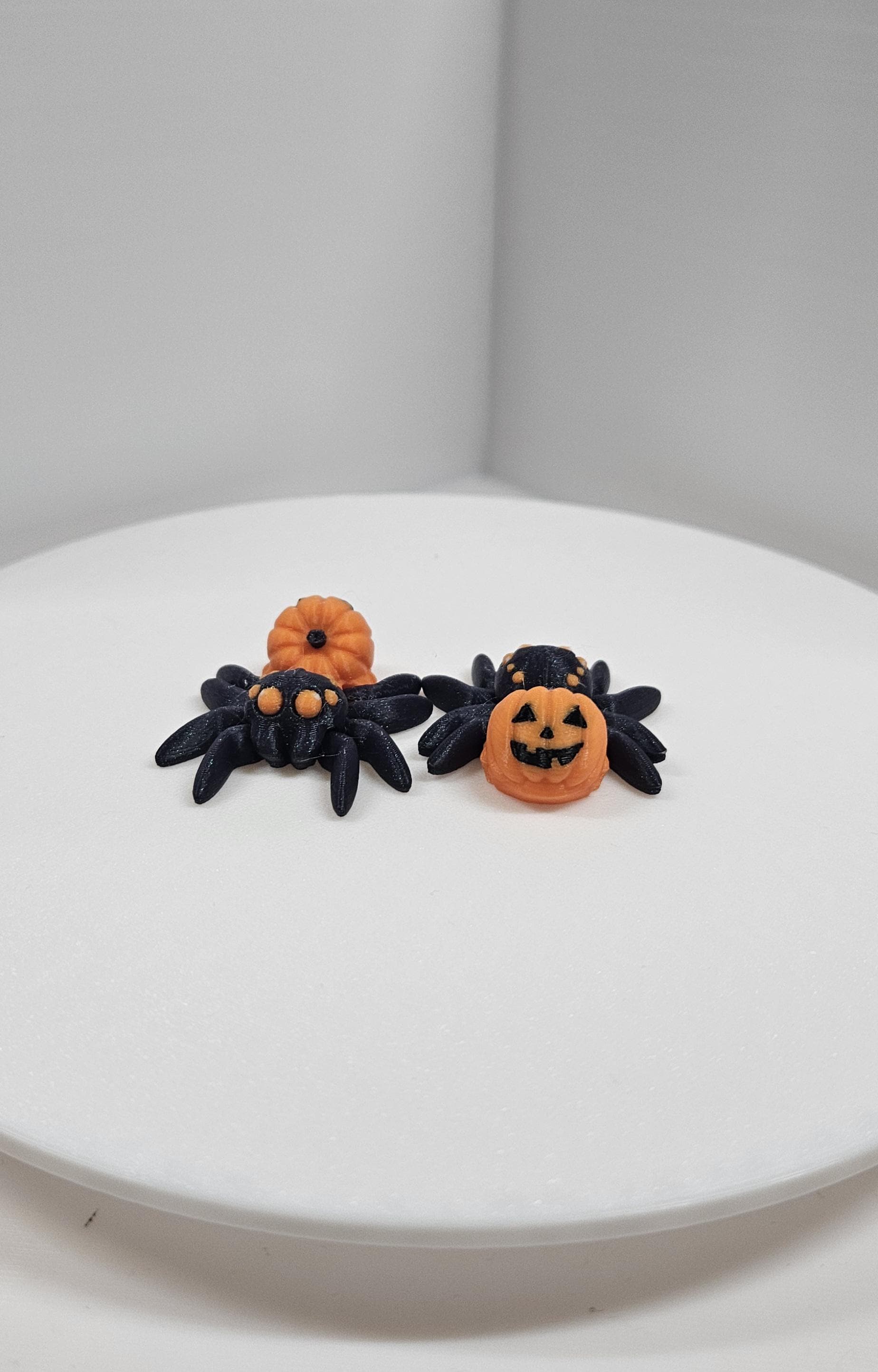 Black 3D printed spider fidget toy with pumpkin decorations for Halloween stress relief