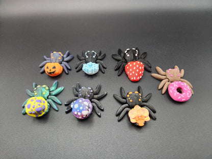 Colorful 3D printed spider fidget toy collection with various patterns on black background