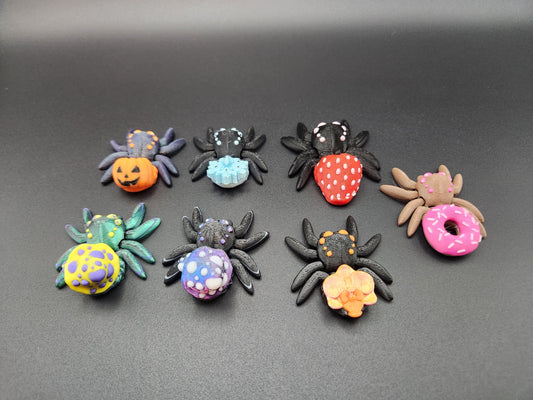 Colorful 3D printed spider fidget toy collection with various patterns on black background