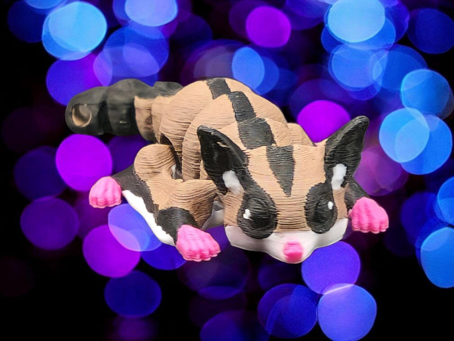 3D printed sugar glider keychain with detailed features and vibrant colors on a colorful bokeh background