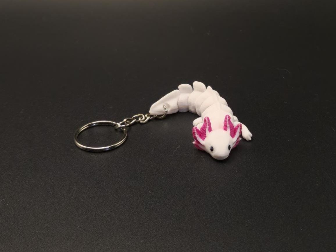 White and pink articulated axolotl keychain with segmented body on black background