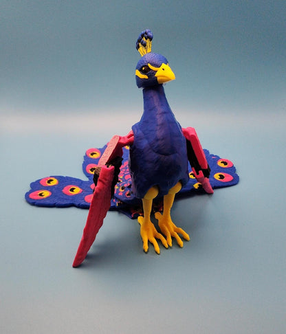 Colorful articulated bird desk decor resembling a peacock with blue, yellow, and pink details