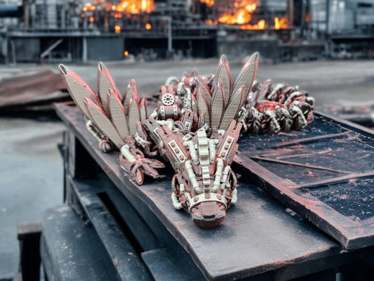Articulated steampunk dragon figurine with mechanical wings and gears displayed on a metal surface