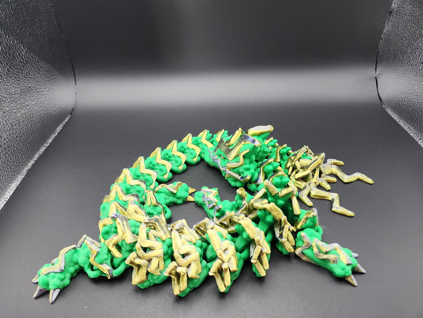 Green and yellow articulated storm dragon figurine with detailed segmented body on black background