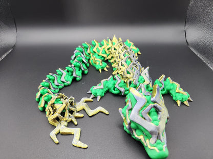 Green and gold articulated storm dragon figurine with detailed spikes and flexible body on black background