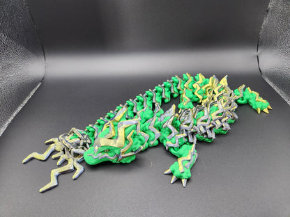 Green and yellow articulated storm dragon figurine with detailed scales and segmented body on black background